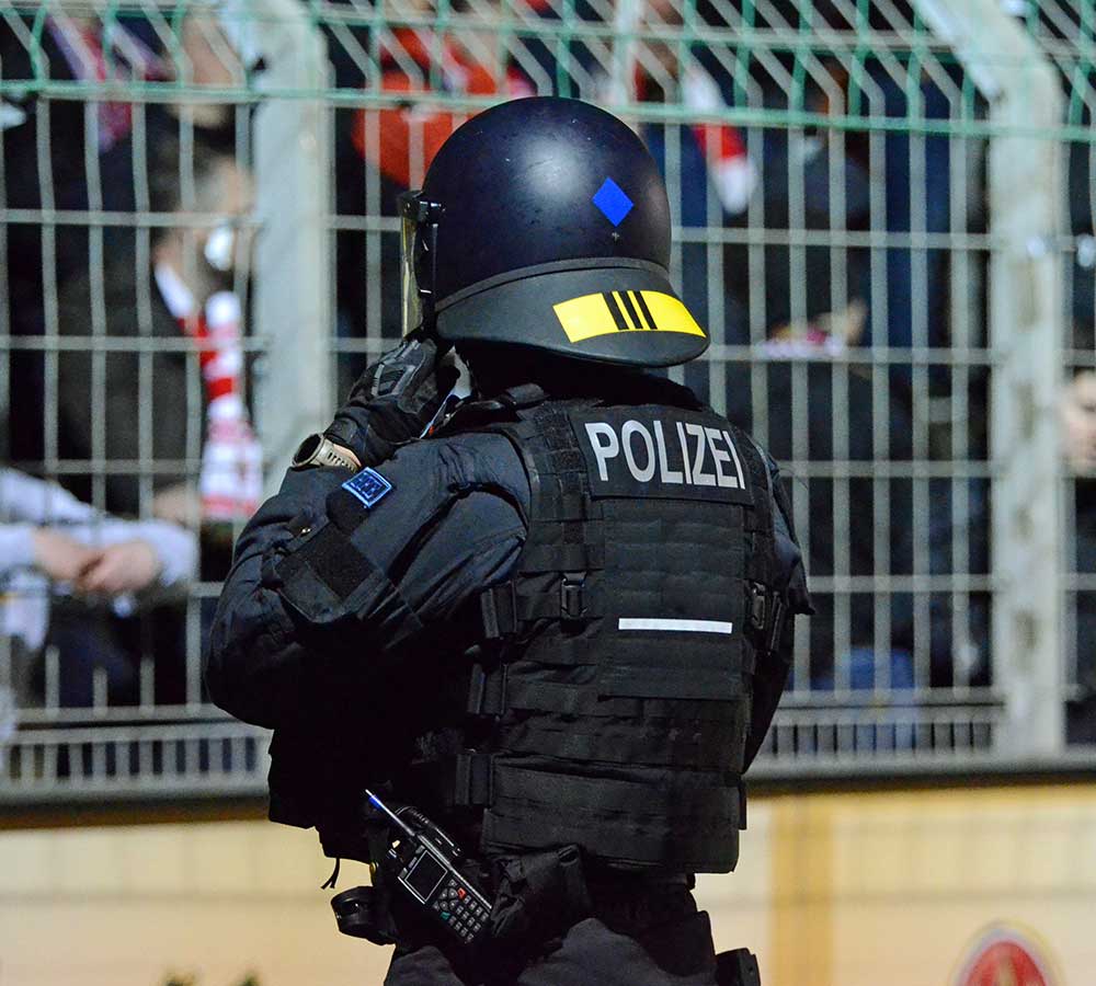 Polizist beobachtet in einem Fußballstadion den Fanblock